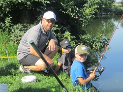 Kinder sitzen beim Teich
